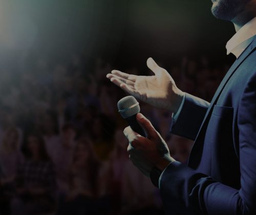 Motivational speaker with microphone performing on stage, closeup